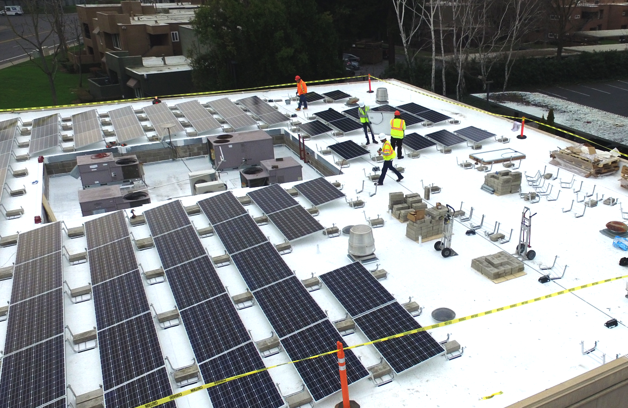 Workers adding panels to roof top solar panels
